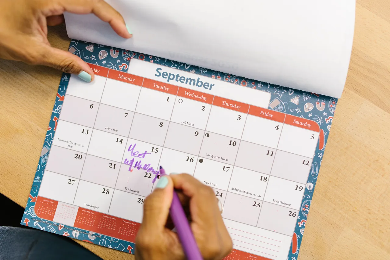 Pessoa a assinalar o mês de setembro num calendário de secretária