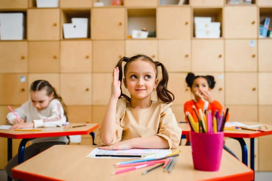 Menina com o braço levantado numa sala de aula portuguesa a participar ativamente na lição