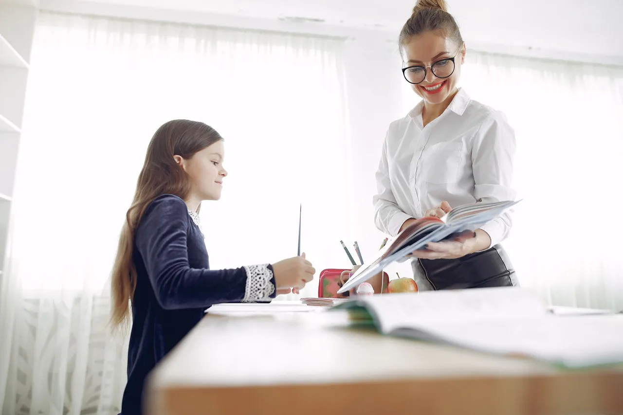 Professora a apoiar individualmente uma criança com os trabalhos escolares