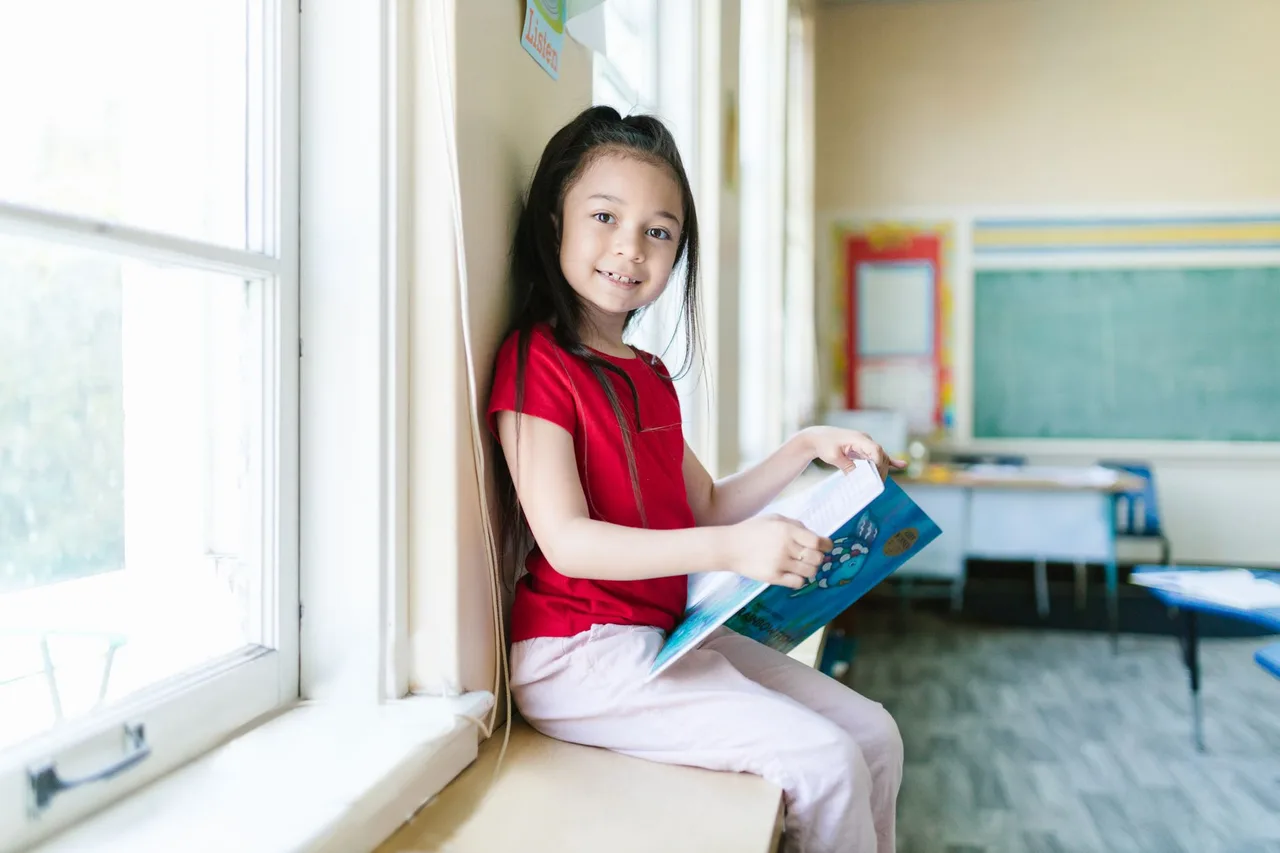 Menina a ler um livro numa sala de aula bem iluminada