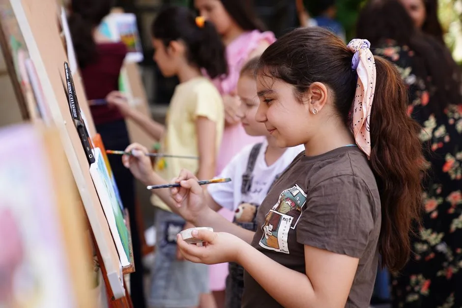 Crianças a pintar ao ar livre numa oficina de artes de verão