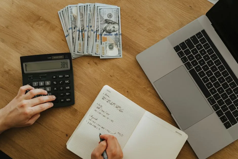 Estudante a calcular despesas mensais com calculadora e apontamentos