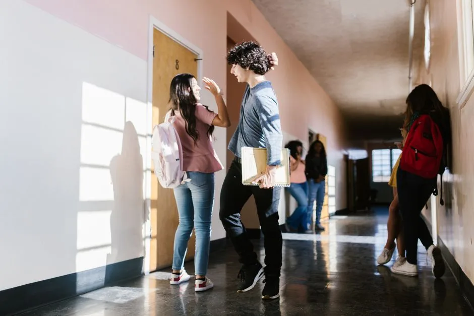 Dois alunos a cumprimentar-se com alegria no corredor da escola, refletindo um ambiente escolar seguro