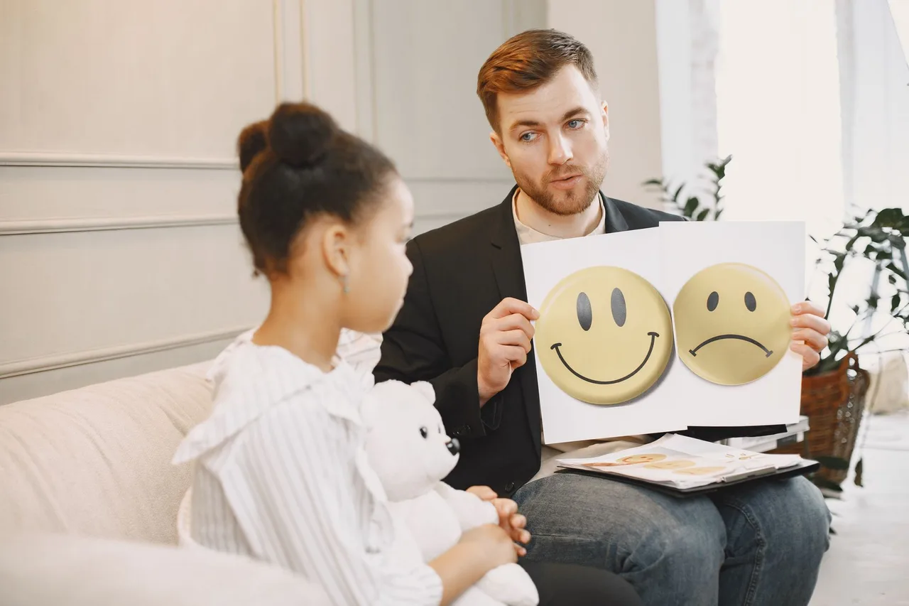 Terapeuta a usar cartões de emoções para apoiar uma criança numa sessão individual