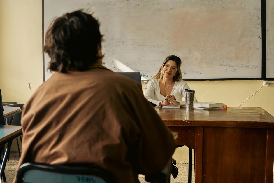 Professor a conversar com aluno numa sala de aula, ilustrando a colocação de docentes nas escolas