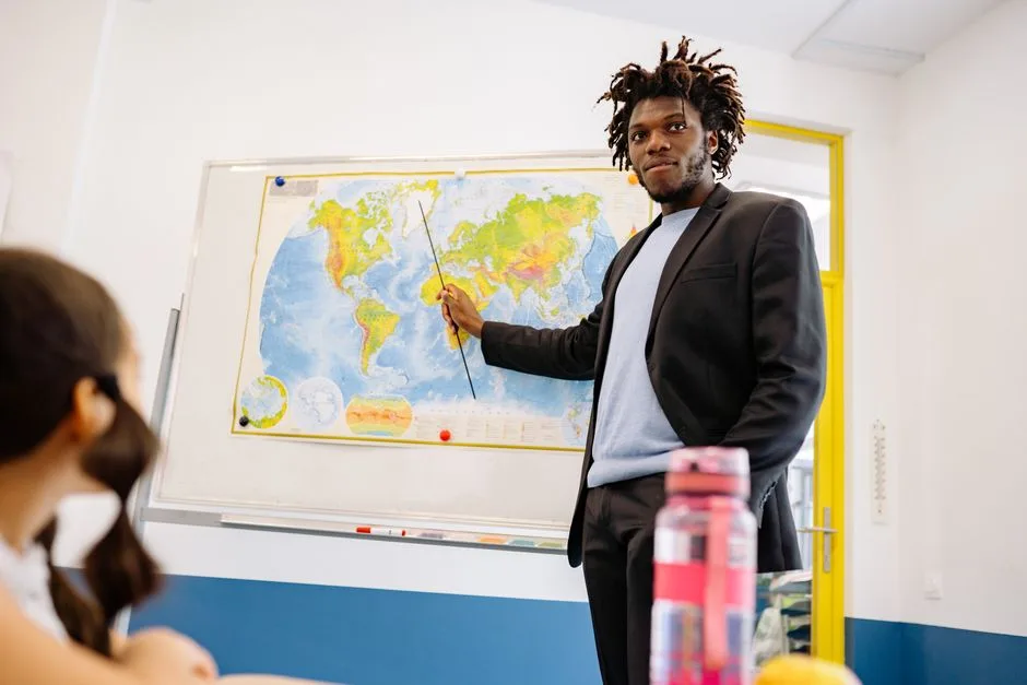 Professor a apontar para um mapa mundo durante uma aula em sala de aula