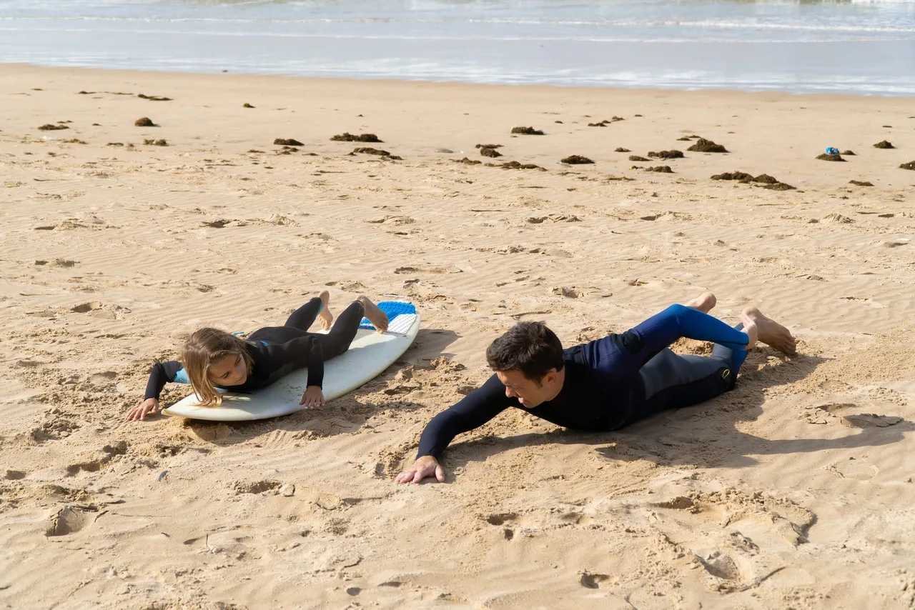 Instrutor a ensinar uma menina a fazer surf numa praia portuguesa