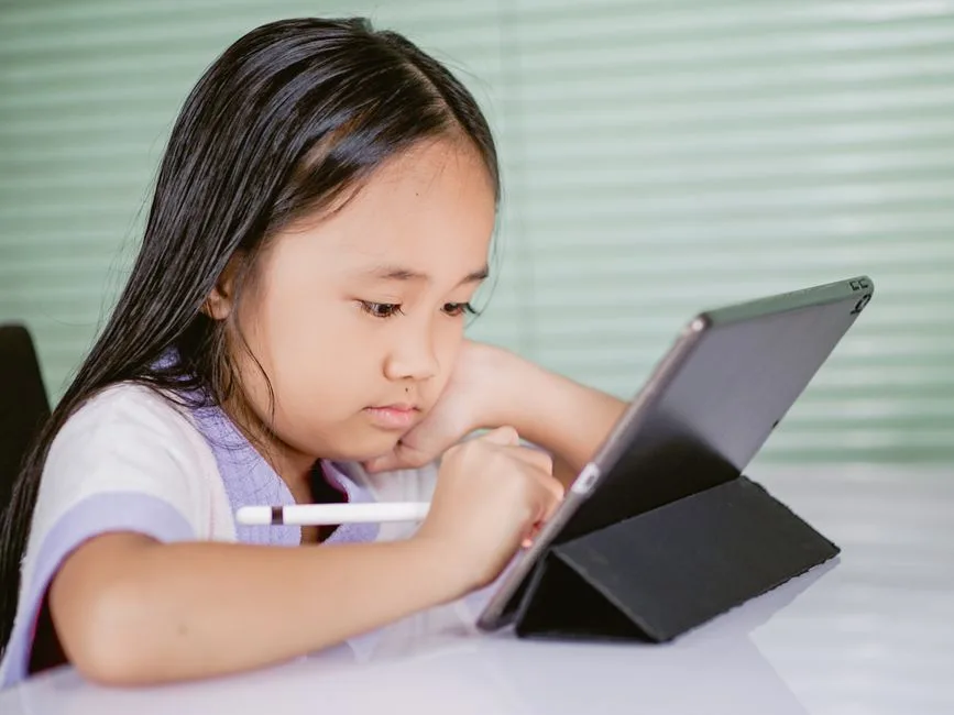 Criança a usar um tablet para aprendizagem digital, ilustrando a integração da IA desde o 1.º ciclo