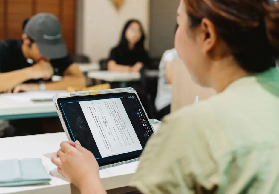 Alunos a usar tablets numa sala de aula, ilustrando a opção por manuais digitais a partir do 2.º ciclo