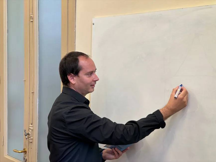Professor a explicar conteúdos num quadro branco em sala de aula, ilustrando o plano de formação docente exigido em 2026/2027