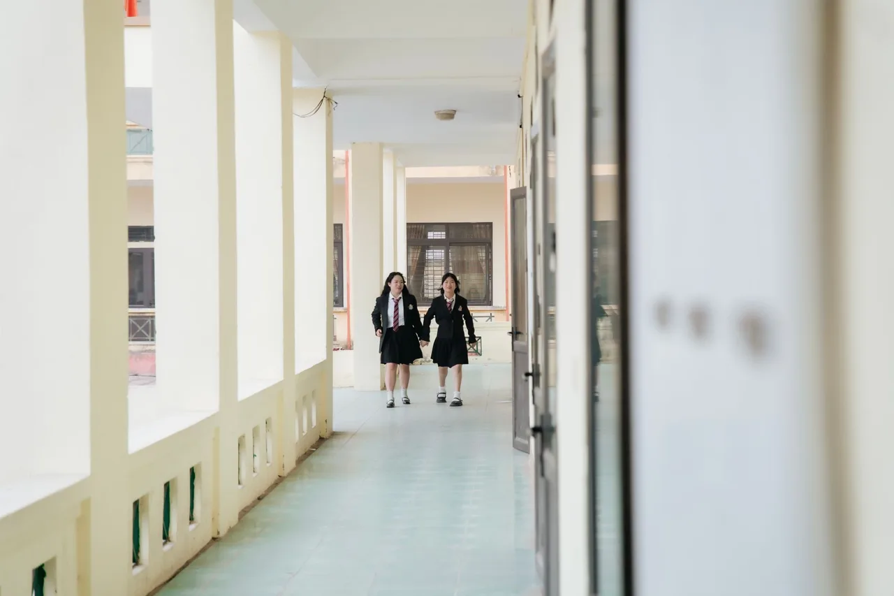 Estudantes a conversar num corredor luminoso de uma escola secundária