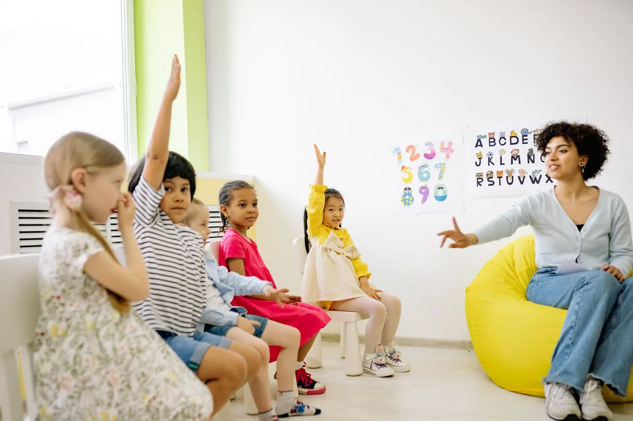 Educadora a dar uma lição a crianças de pré-escolar numa sala de aula colorida