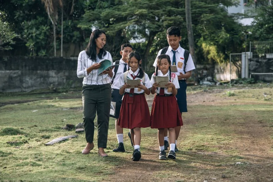 Crianças a caminhar acompanhadas por uma professora, já integradas na nova rotina escolar
