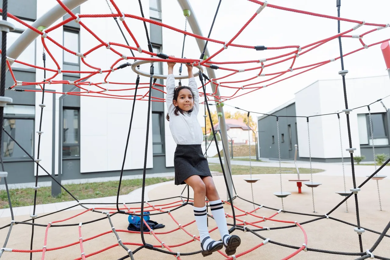Crianças a brincar num parque infantil da escola, um dos contextos cobertos pelo seguro escolar