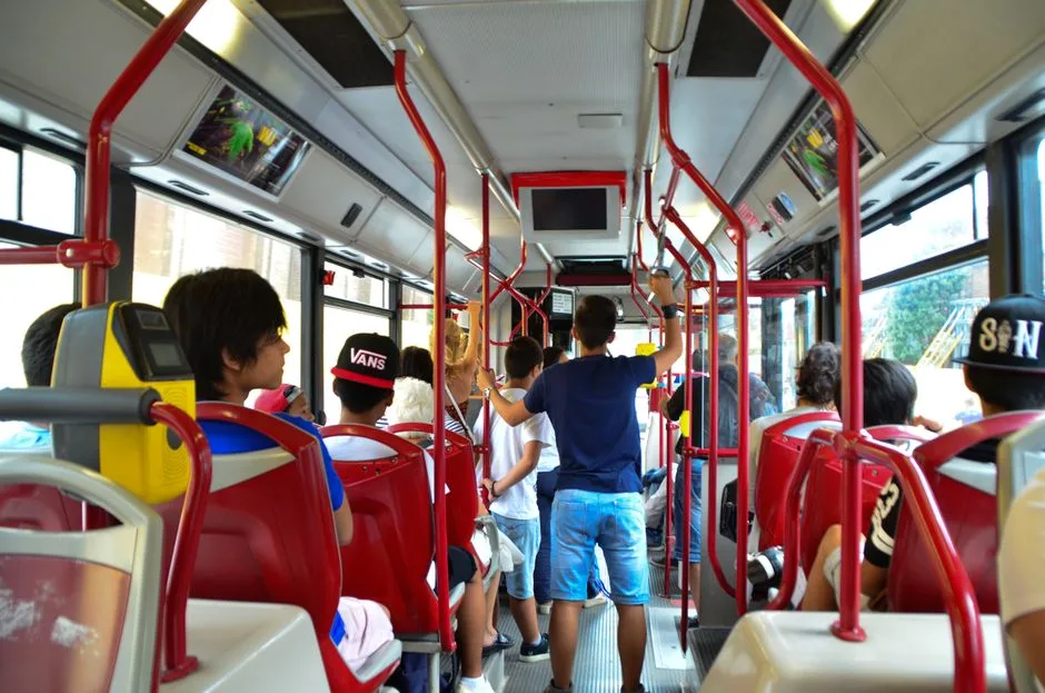 Interior de um autocarro urbano com passageiros durante o trajeto para a escola